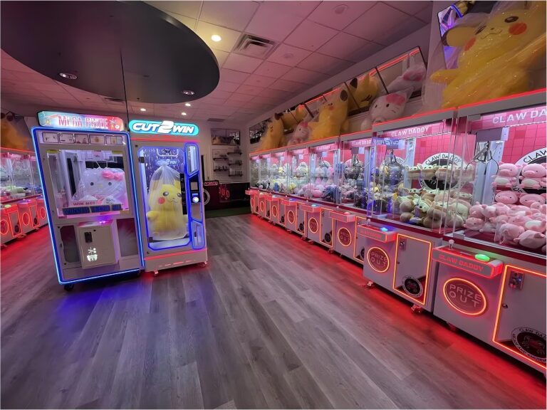 Arcade interior with red LED rows of claw machines and large-prize cabinets, demonstrating real-world deployment and high-traffic setup.