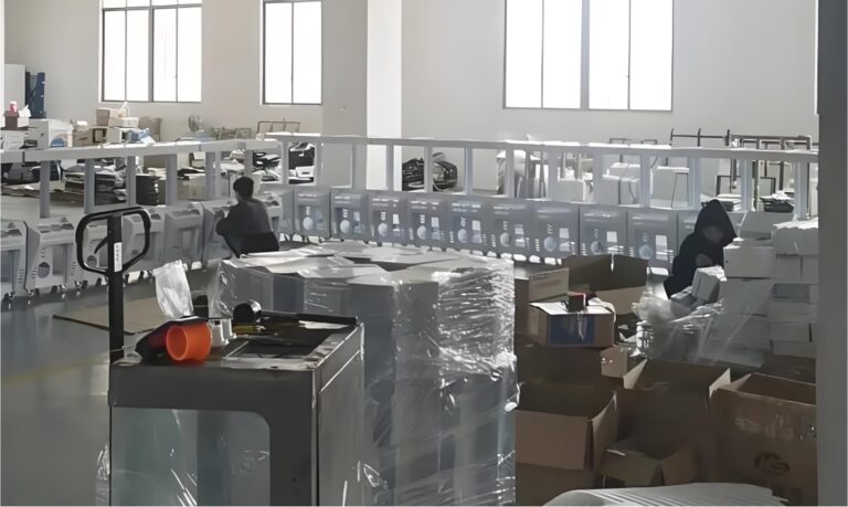 Assembly workshop at Leyou factory with technicians installing claw machine cabinets