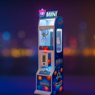 Mini claw machine with space-themed cabinet in a colorful arcade.
